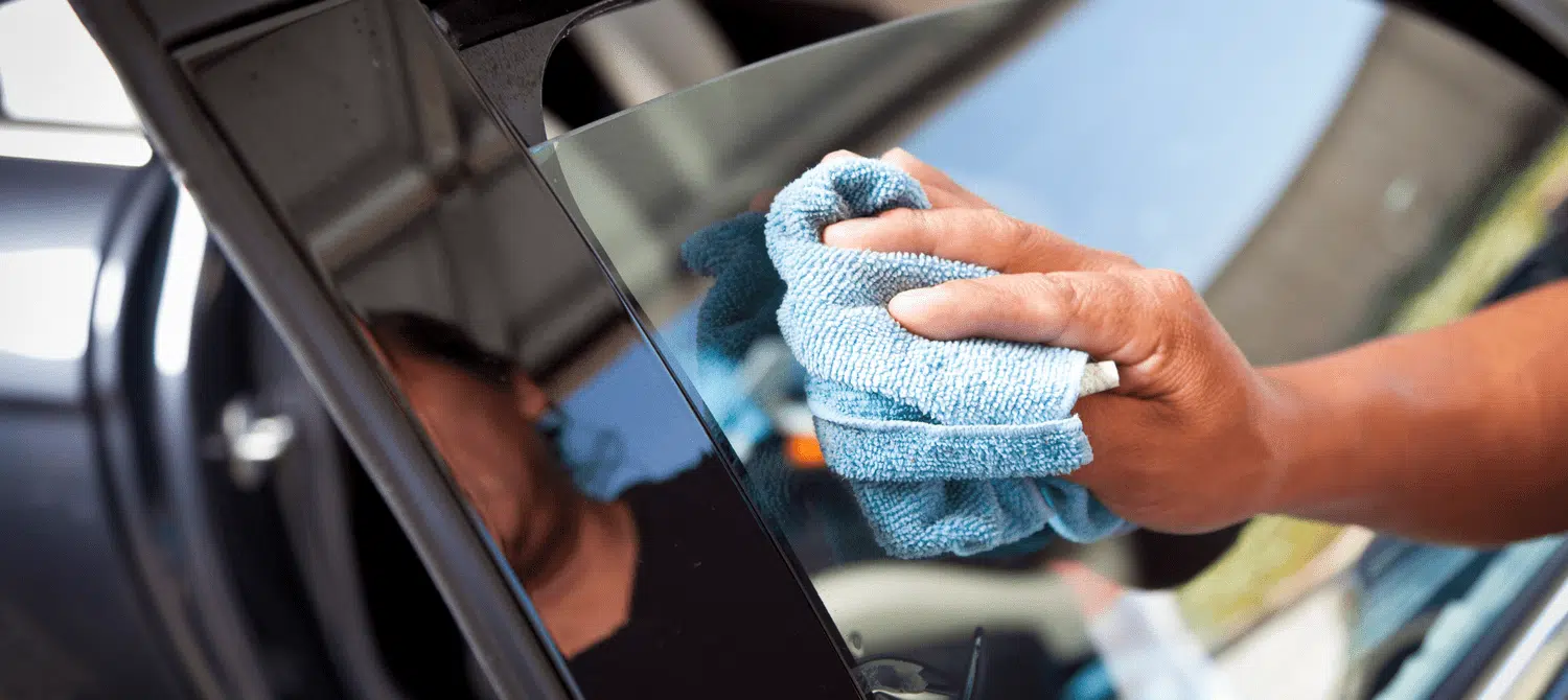 Professional tint shop technician installing car window tint in Orange County