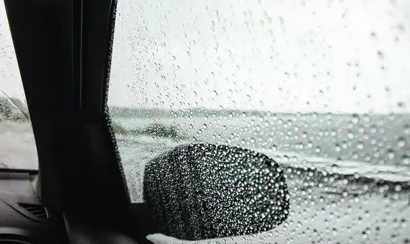 Rain beading on a freshly tinted car window during the first 72 hours after installation