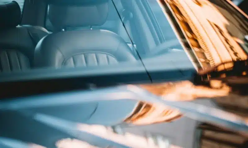 Close-up of a tinted car side window from inside, showing warm light reflections on the glass